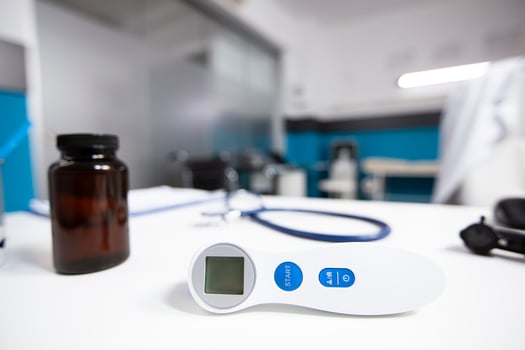 Modern doctors office with thermometer and medication bottle neatly arranged on desk. Closeup of medical instrument used for checking temperature of patient during consultation. photo