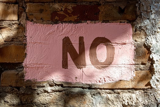Pink painted brick wall with the word NO in brown paint photo