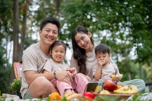 Caring Asian parents enjoy a picnic in a public park with their little kids. photo