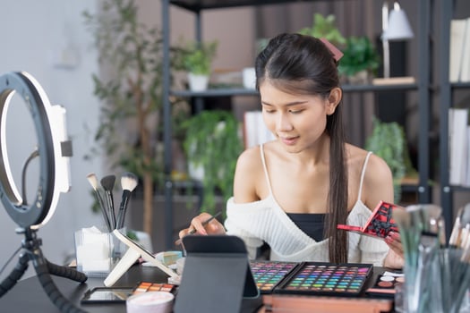 woman beauty influencer makeup artist vlogger live streaming makeup tutorial on smartphone for social media photo