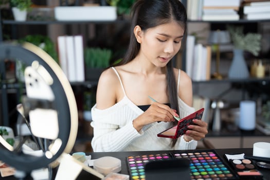 woman beauty influencer makeup artist vlogger live streaming makeup tutorial on smartphone for social media. photo
