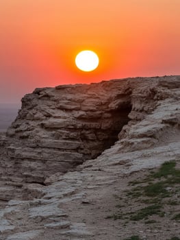 Sunset over rocky landscape with cave photo