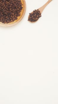 Dried Cloves on Wooden Plate and Spoon on Light Background photo