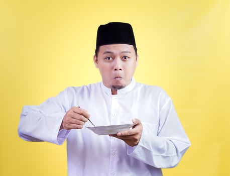 asian man in traditional attire eagerly enjoys a meal photo