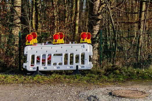 Construction barrier with warning lights placed near a wooded area photo