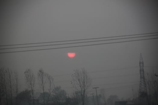 The sun is setting behind a power line photo