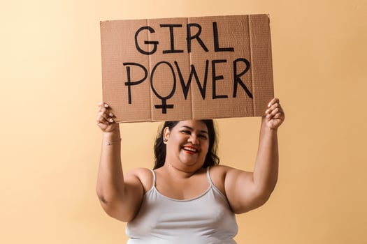 Latinx adult woman holding up hands with girl power banner over. photo