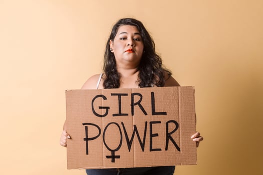 Adult latinx woman hold a placard. feminism concept. Oversized woman looking away and smiling with girl power banner over. photo