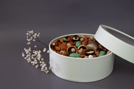 On a light background there is a round box filled with various nuts and dried fruits. Mothers Day. Valentine's Day. International Women's Day.A delightful gift. Low-fat food. photo