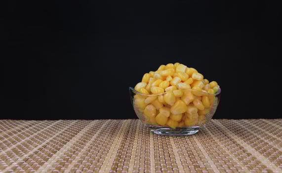 Transparent glass cup with canned corn.Canned corn kernels.... photo