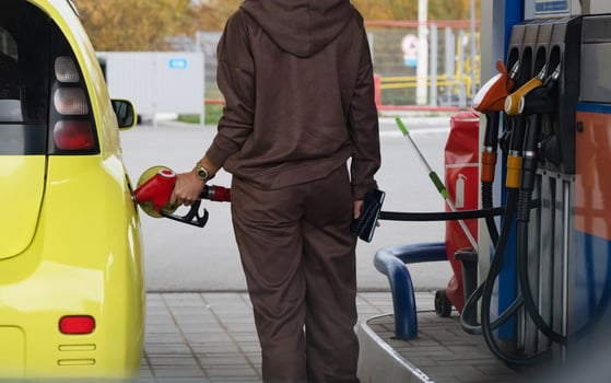 Pumping gas at the gas pump. The woman refuels the car. A woman at a gas station. A woman refuels a car with gasoline at a gas station. Fuel injection into the tank. Detail of a woman filling a car photo