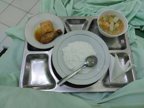Hospital Meal on Tray Featuring Rice Porridge, Vegetables, and Chicken Dish photo