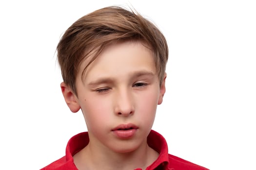 The face of a teenage boy in close-up. He closed one eye. photo
