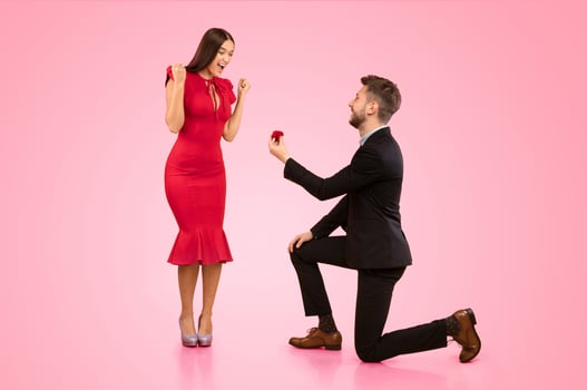 She Said Yes. Man Proposing To Girlfriend Offering Her Ring In Box Standing On Knee Over Yellow Background In Studio photo
