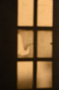 Soft sunlight filters through a weathered window casting shadows in a quiet room photo