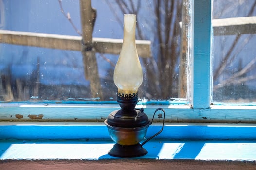 Used flat-wick kerosene lamp also known as a paraffin lamp on old shabby blue windowsill in the sunlight photo