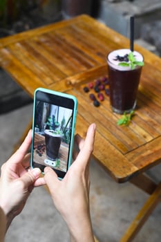 Hand holding a phone taking picture of mulberry tea for advertisement photo