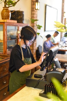 Young Vietnamese waitress serving customer at the checkout in cafe. photo