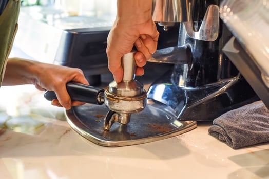 Hands pressing coffee beans for a coffee machine close up photo
