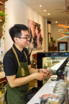 Vietnamese waiter works with cashier machine in a cafe photo
