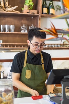 Vietnamese waiter works in counter with cashier machine in cafe photo