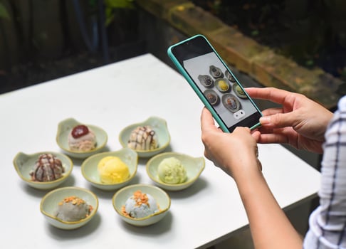 A woman taking picture of many ice cream on white table photo