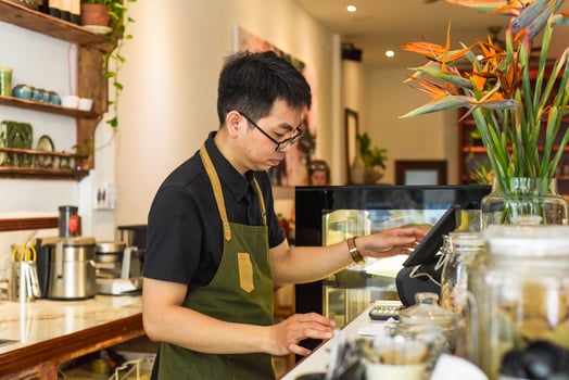 Vietnamese waiter works in counter with cashier machine in a cafe photo