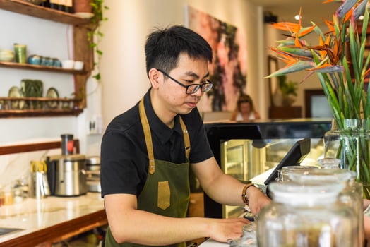 Vietnamese waiter works in the counter with cashier machine in a cafe photo