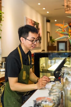Vietnamese waiter works with counter with cashier machine in a cafe photo