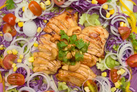 Pan fried chicken on purple plate with greens and mulberry sauce on wooden table photo