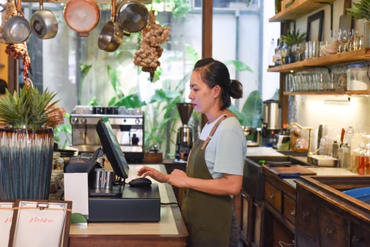 Young Vietnamese waitress works with check out machine in cafe photo