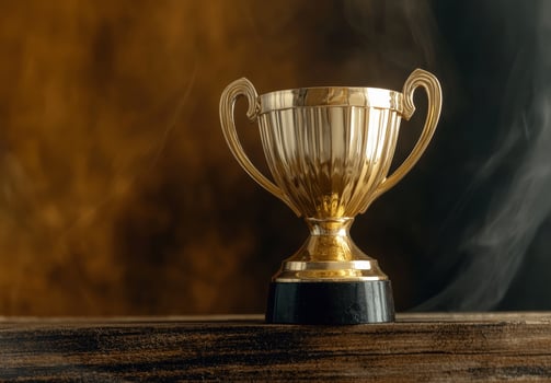 Golden trophy on wooden surface with smoke background photo