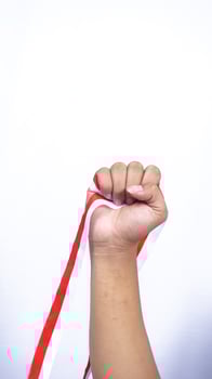 Man's Clenched Fist Holding Red and White Ribbons on White Background photo