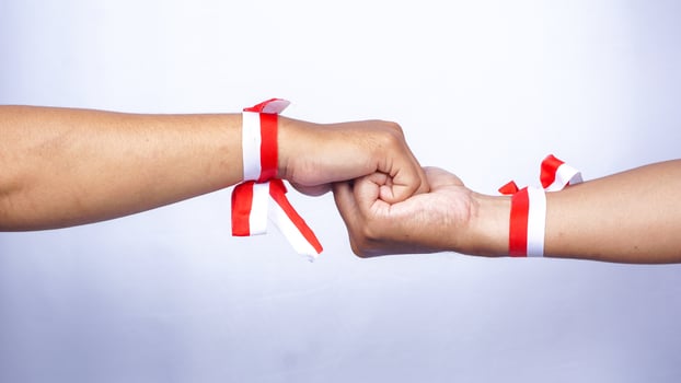 Two Hands Wearing Red and White Ribbons Holding Each Other on White Background photo