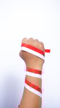 Man's Clenched Fist with Red and White Ribbons Wrapped Around The Hand on White Background photo