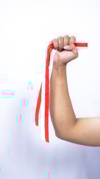 Hand Holding Red and White Ribbons with Clenched Fist on White Background photo