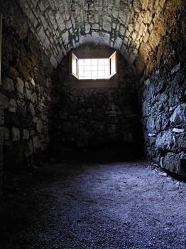 Medieval dungeon with stone walls and a small hatch photo