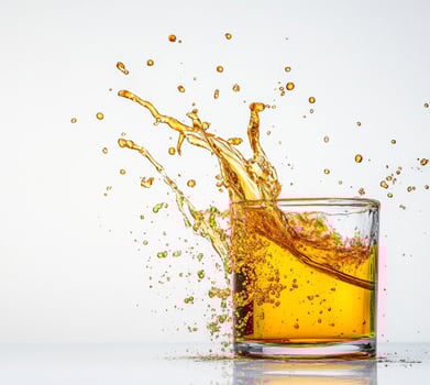 Liquid honey splashes dramatically from a clear glass, creating beautiful droplets against a bright background. The moment captures the essence of movement and sweetness in an artistic display. photo