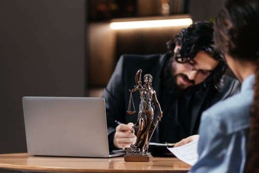 Statue of Justice with scales and a male lawyer working on a laptop. Legal consultations and decision-making using modern technology for efficient legal solutions. photo