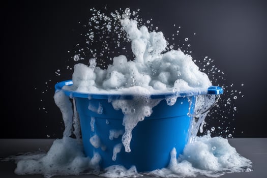 Blue bucket overflowing with soap suds and splashing water photo