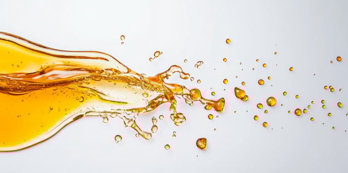 Golden honey splashes across a light surface, creating droplets and a flowing texture. The liquid displays a rich hue that conveys sweetness and fluid movement, capturing a dynamic moment. photo