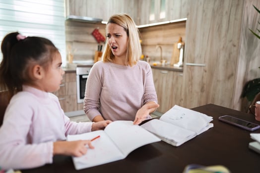 Mom helps daughter with homework while feeling frustrated at the kitchen table photo