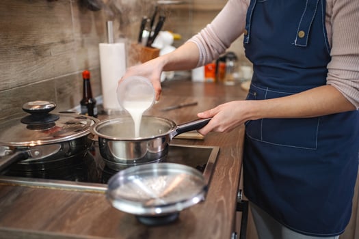 Pouring milk into a pot while preparing a delicious home-cooked meal photo