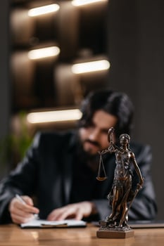 Themis, scales of justice close-up on the desk. Successful African American Attorney Lawyer using a laptop, computer in a courtroom setting. Justice and law, court judge. Vertical photo