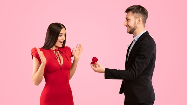 Marry Me Concept. Man Proposing To Woman Giving Her Engagement Ring Standing On Yellow Studio Background. Panorama photo