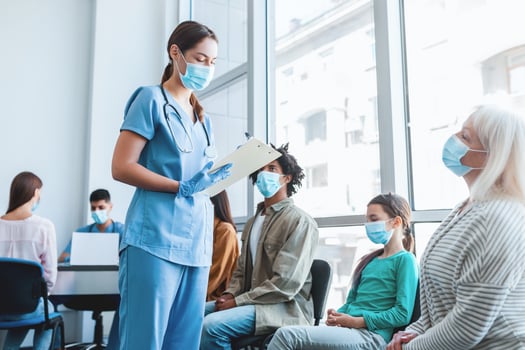 Diverse people sitting in line waiting for their turn to get shots at the hospital vaccination center. Nurse talking with patients in queue for antiviral flu vaccine photo