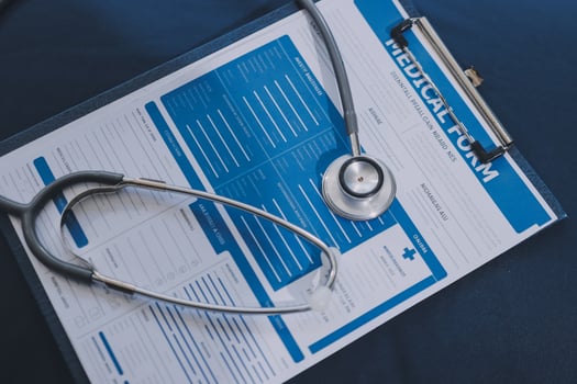 A medical stethoscope is placed on a clipboard with a medical form photo