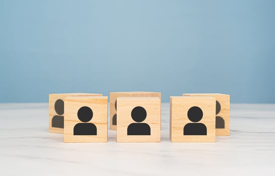 Wooden cubes with people icons over a marble table with a light blue background photo