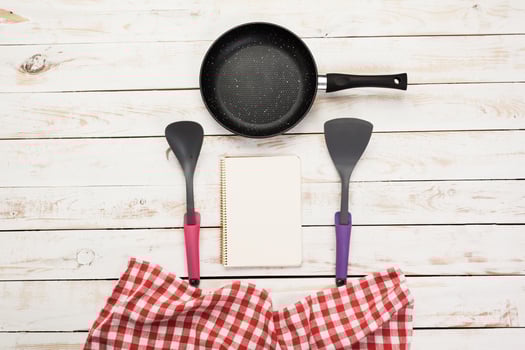 Cast iron pan and other kitchen utensils on wooden table, top view photo
