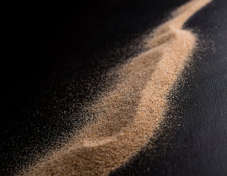 Front View of Dry Brown Sand on a Dark Black Surface photo